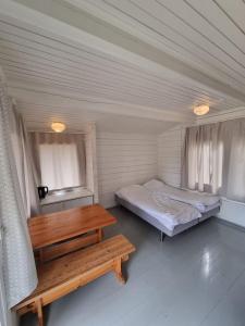 a room with two beds and a wooden table at Kirjurin Leirintä in Pori