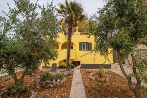 a yellow house with trees in front of it at Sunce 1 in Vrbnik