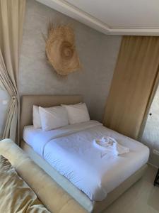1 cama con sábanas blancas y almohadas en una habitación en Maison D'hôtes Des Belges, en Dakhla