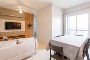 a dining room with a white table and a tv at Curta Praia do Quilombo - Lunata in Penha