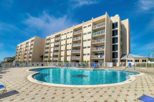 a hotel with a swimming pool in front of a building at Beach House Condominiums B101 - Beachfront with Pool, WiFi, & Beach Service in Destin