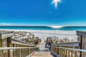 a stairway to the beach with the ocean in the background at Beach House Condominiums B101 - Beachfront with Pool, WiFi, & Beach Service in Destin