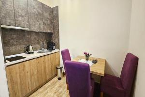 a small kitchen with a wooden table and purple chairs at Villa Montemaris Budva in Budva