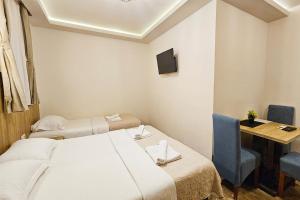 a room with two beds and a table and a television at Villa Montemaris Budva in Budva