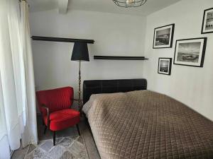 a bedroom with a bed and a red chair at Apartament i domki wakacyjne w uroczym zakątku Ustki in Ustka