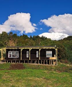 a house in a field with mountains in the background at Casa Pumahue in La Ensenada