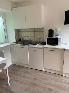 a small kitchen with white cabinets and a microwave at Charmant Appartement in Saint Malo