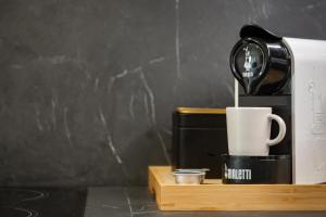 eine Kaffeemaschine und eine Tasse auf einem Holztablett in der Unterkunft Moscova Luxury Home in Mailand