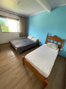 een slaapkamer met 2 bedden en een blauwe muur bij Pousada Hawaii in Barra Velha