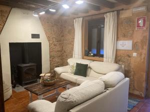 a living room with two white couches and a fireplace at Casa rural La Piedrapipa in Madrigal de la Vera