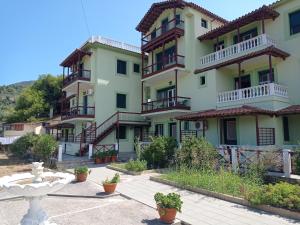 un gran edificio de apartamentos con balcones y una fuente en Alexandros Rooms & Studios, en Skopelos Town