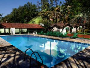 a large swimming pool with green chairs around it at Vila Francesa Hotel in Penedo