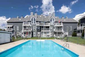 a large house with a swimming pool in front of it at Condo-piscine à 200M du Memphré in Magog-Orford