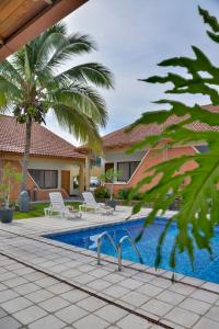 una piscina con 2 sillas y una casa en Apartotel Obelisco San José Aeropuerto, en San José