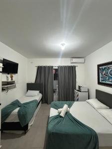 um quarto de hotel com duas camas e uma televisão em Suítes Moreira em Penha