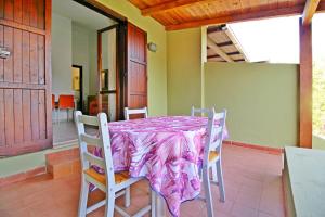 mesa de comedor con sillas y mantel púrpura en Bilo Blu Holiday a 80 metri dal mare, en Costa Rei