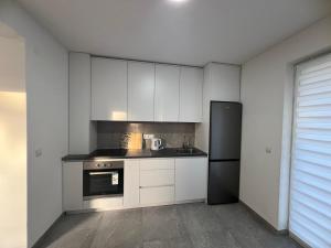 a kitchen with white cabinets and a black refrigerator at Old Town Hideaway in Sarajevo