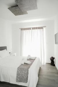 a bedroom with a white bed and a large window at Filokalia 7 - Premium Vacation House with Sea View in Karistos