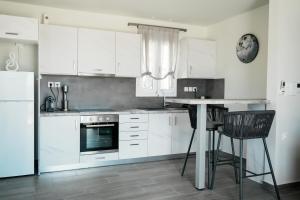 a kitchen with white cabinets and a table and chairs at Filokalia 7 - Premium Vacation House with Sea View in Karistos +5 photos