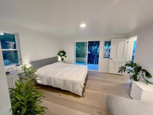 Un dormitorio con una cama blanca y algunas plantas en New Listing -Luxury House on the Riviera , Modern Design, and Panoramic Ocean -30 day Minimum en Santa Bárbara
