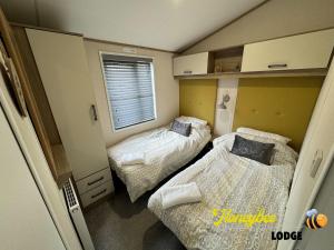 Habitación pequeña con 2 camas y ventana en Honeybee Lodge, en Morpeth