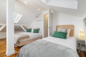 two beds in a white room with green pillows at WHome Brand New Lisbon Rooftop with River View in Lisbon