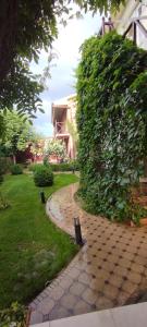 a garden with a brick walkway next to a large bush at Green House ECO HOTEL in Samarkand