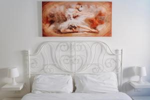 a bedroom with a white bed with a painting above it at Camera Demetra in Syracuse