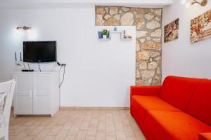 een woonkamer met een rode bank en een tv bij Casa Demetra in Siracusa
