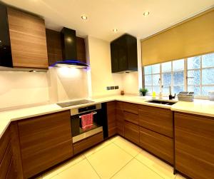 a kitchen with wooden cabinets and a sink and a window at The Kings Palace Central London by Wild in London