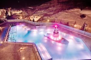 a swimming pool at night with a fountain at Hotel Alpenblick-Leukerbad-Therme in Leukerbad