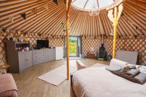 a room with a bed and a tv in a yurt at Glamp and Tipple Ltd in Great Ellingham