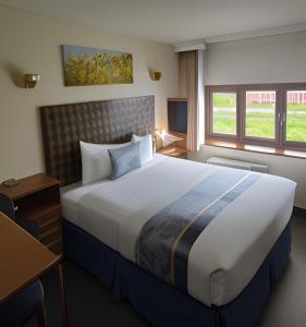 a hotel room with a large bed and a desk at Golden Lion Hotel in Rugby