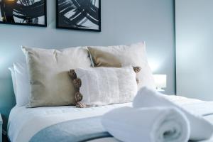 un letto con lenzuola e cuscini bianchi in una camera da letto di Lux 3 Bed 10 mins from Centre - Parking & Netflix a Manchester