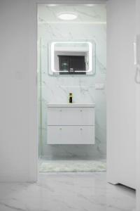 ein weißes Badezimmer mit einem Waschbecken und einem Spiegel in der Unterkunft Apartament Sonata in Zielona Góra