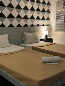 dos camas sentadas una al lado de la otra en una habitación en ACME Inn Subic, en Olóngapo