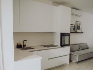 a kitchen with white cabinets and a couch at Studio apartment G13 in Đakovo