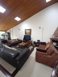 ein Wohnzimmer mit Ledersofas und einem TV in der Unterkunft Amplia Casa Familiar in Bogotá