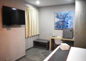 a small room with a desk and a tv at Attraction Hotel Deluxe in Playa del Carmen