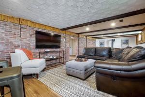 uma sala de estar com um sofá de couro e uma parede de tijolos em La Riviera - Cottage in the City em Gatineau