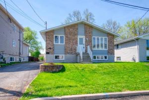 une maison en briques avec une cour herbeuse dans l'établissement La Riviera - Cottage in the City, à Gatineau