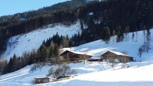 une montagne enneigée avec des maisons sur une pente dans l'établissement Apartments Teglbauernhof, Hütte, Chalet, Mobilheim, Appartement, Ferienwohnung, Pension, Urlaub, à Uttendorf