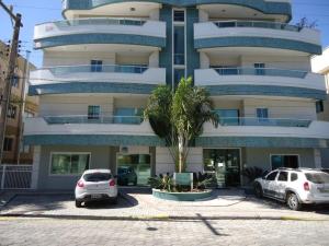 zwei Autos parkten vor einem großen Gebäude in der Unterkunft A15 - APARTAMENTO 2 DORMITÓRIOS NO CENTRO DE BOMBINHAS ALUGUEL DE TEMPORADA in Bombinhas