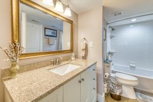 a bathroom with a sink and a toilet and a mirror at Beach House Condominiums B101 - Beachfront with Pool, WiFi, & Beach Service in Destin