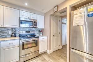 a kitchen with white cabinets and a stove and a refrigerator at Beach House Condominiums B101 - Beachfront with Pool, WiFi, & Beach Service in Destin
