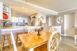 a kitchen and dining room with a wooden table and chairs at Beach House Condominiums B101 - Beachfront with Pool, WiFi, & Beach Service in Destin