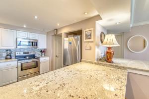 a kitchen with white cabinets and a granite counter top at Beach House Condominiums B101 - Beachfront with Pool, WiFi, & Beach Service in Destin