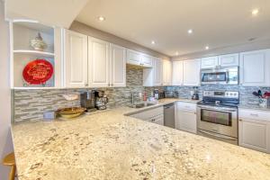 a kitchen with white cabinets and a granite counter top at Beach House Condominiums B101 - Beachfront with Pool, WiFi, & Beach Service in Destin
