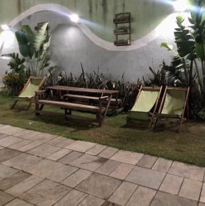 zwei Stühle und eine Bank neben einer Wand mit Pflanzen in der Unterkunft OPEN HOUSE VARGAS in São Paulo