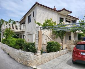 a house with a stone retaining wall in front of it at Apartments Mia in Okrug Gornji